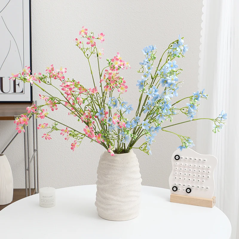 Artificial flower branch with delicate blue flowers and green berries