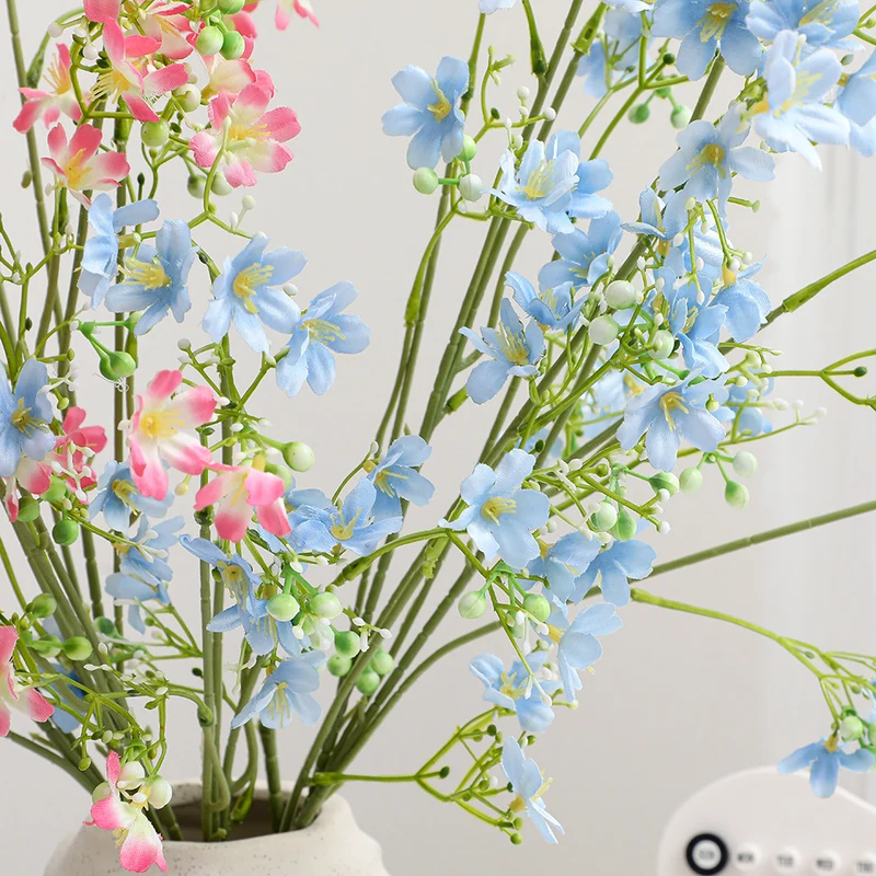 Artificial flower branch with delicate blue flowers and green berries