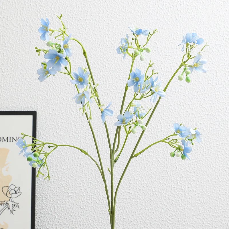 Artificial flower branch with delicate blue flowers and green berries