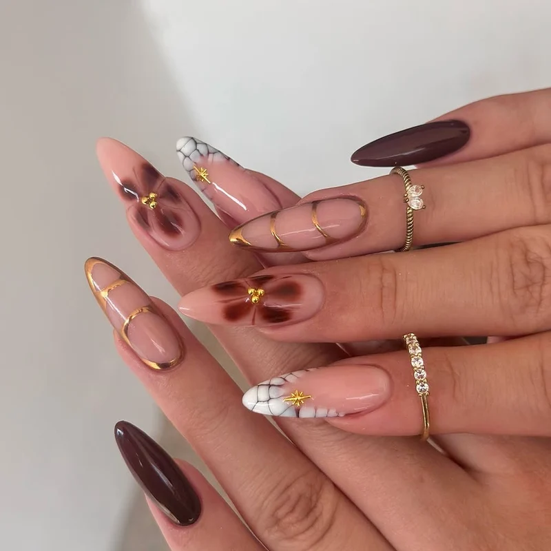 Artful Stiletto nails with gold accents and decorative floral designs Stornfield