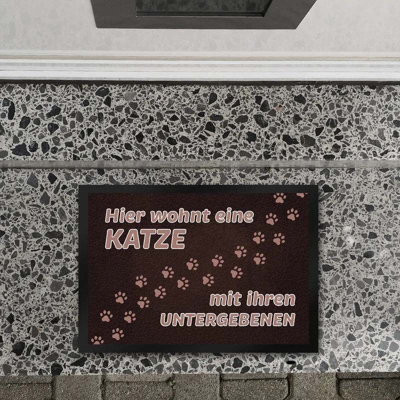 Hier wohnt eine Katze mit ihren Untergebenen Fußmatte mit Pfotenabdrücken