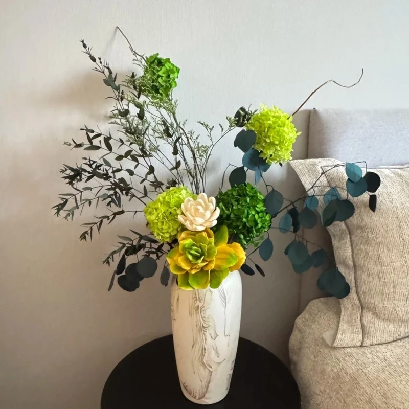 Lebensechte Sukkulente und Blumenarrangement