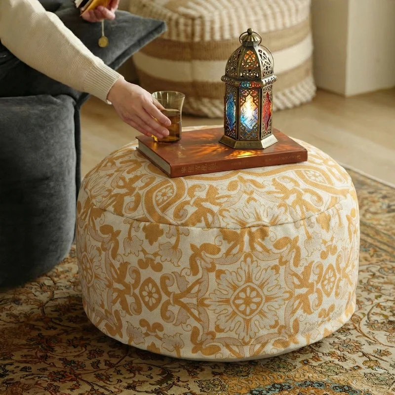 Round floor pouf with woven ornament pattern and carrying handle Stornfield
